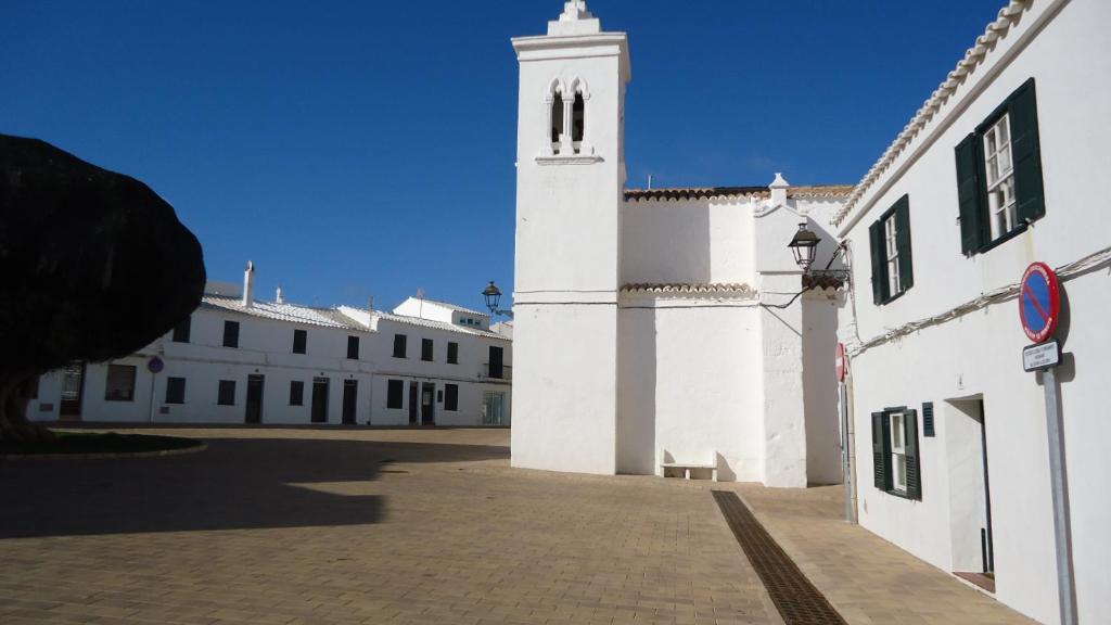 un gran edificio blanco con una torre de reloj en ESGLESIA 4 by SOM Menorca, en Fornells