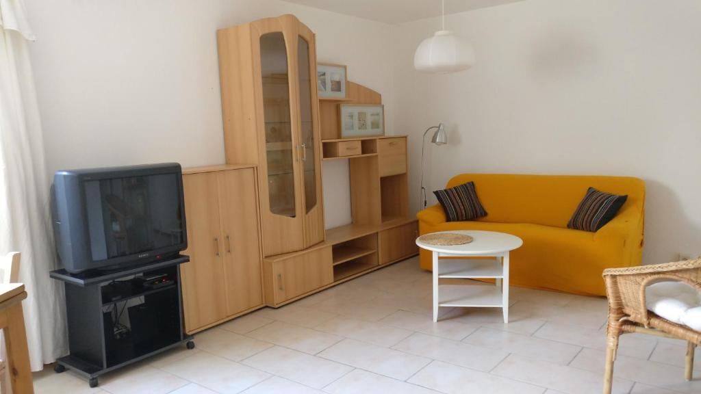 een woonkamer met een gele bank en een tv bij Fanny in Wittlingen