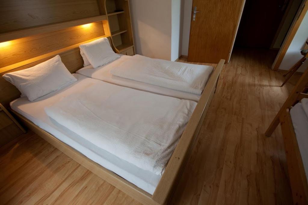 łóżko z białą pościelą i poduszkami na drewnianej podłodze w obiekcie Gasthof Jaegerwirt w mieście Zederhaus