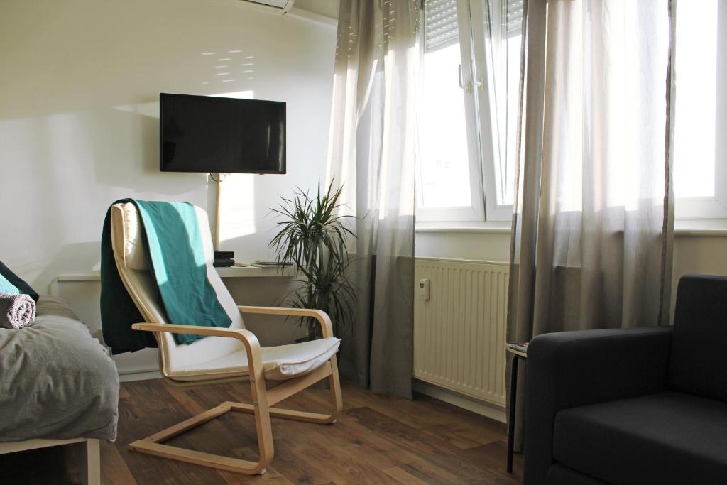 a bedroom with a chair and a tv and a bed at Studio apartman in Zagreb