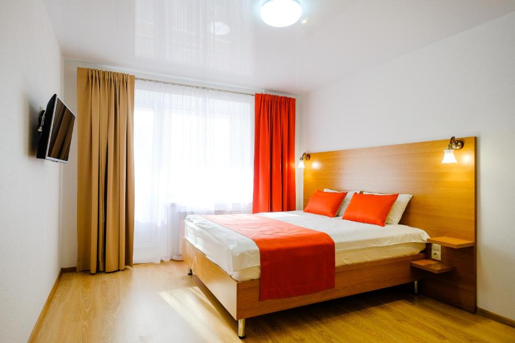トムスクにあるApart Petrovskie on Matrosova 3のベッドルーム1室(オレンジ色の枕と窓付)