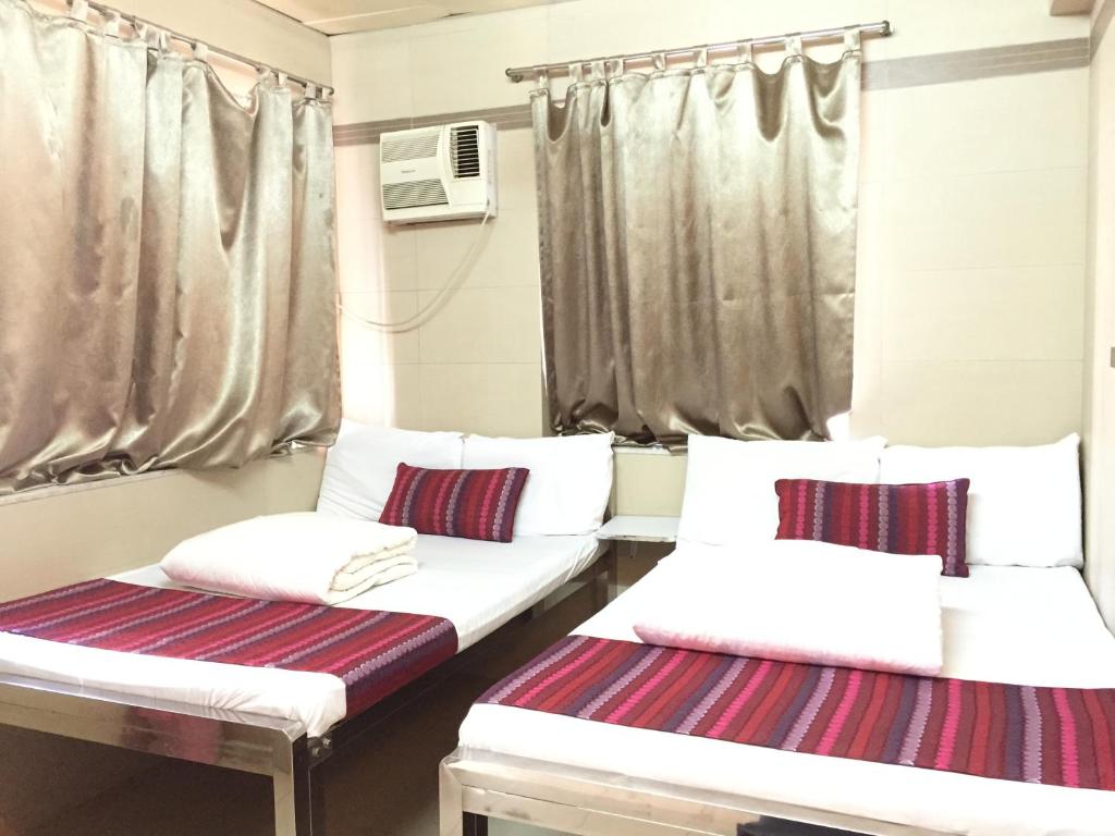 2 camas en una habitación pequeña con cortinas en Osaka Hostel, en Hong Kong