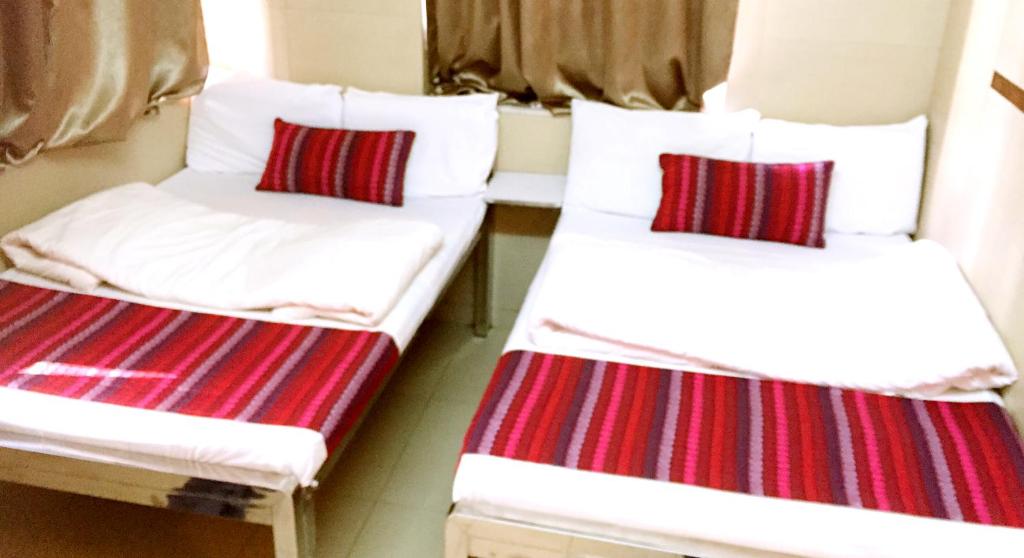 2 Betten in einem Zimmer mit roten und weißen Streifen in der Unterkunft New Grand Guest House in Hongkong