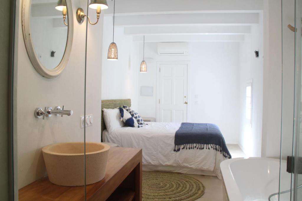 a bathroom with a bed and a sink and a mirror at S'Esparteria Hotel in Ciutadella