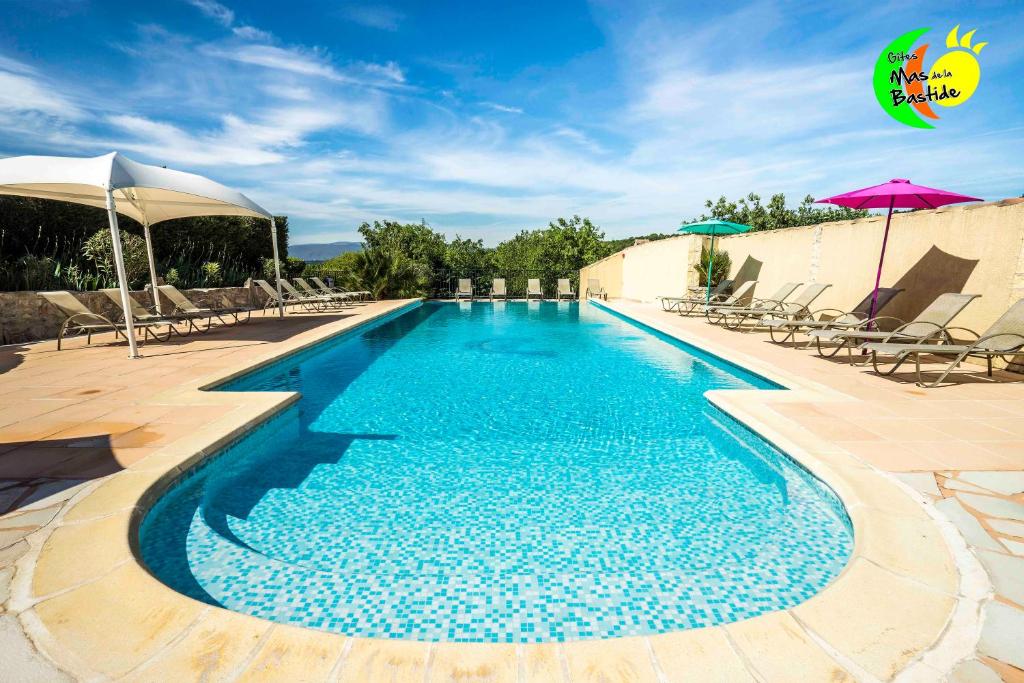 - une piscine avec des chaises et des parasols sur une terrasse dans l'établissement Village de gites Mas de la Bastide, à Joyeuse