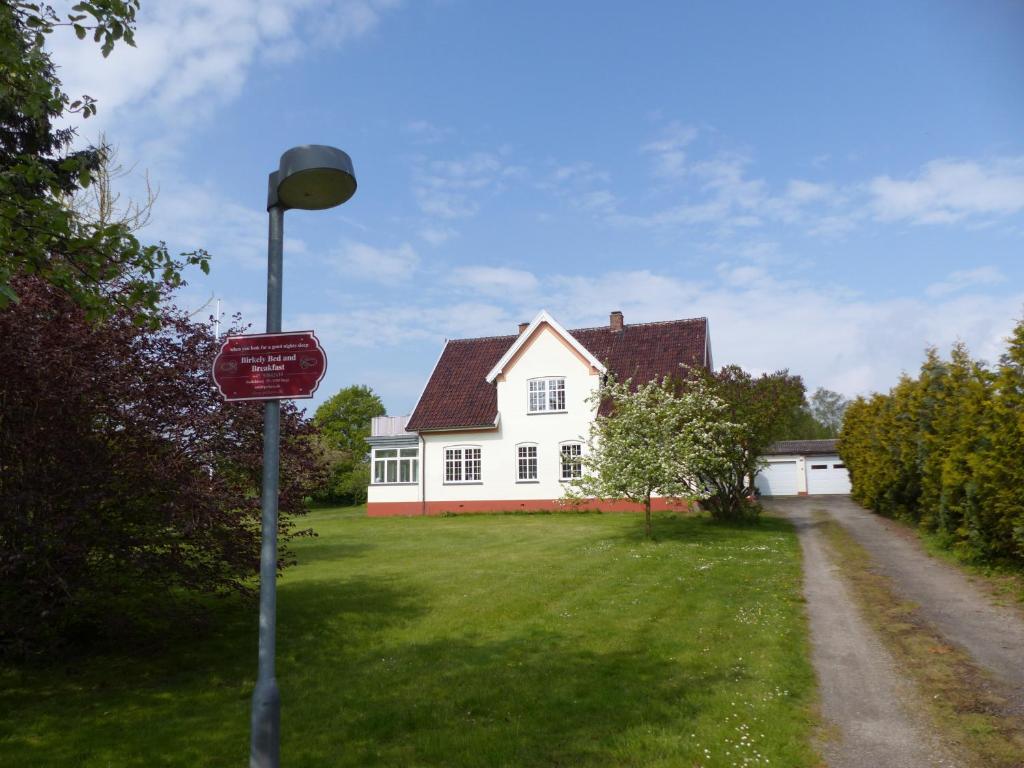 a white house with a red house on the side of the road at Birkely Bed and Breakfast in Stege