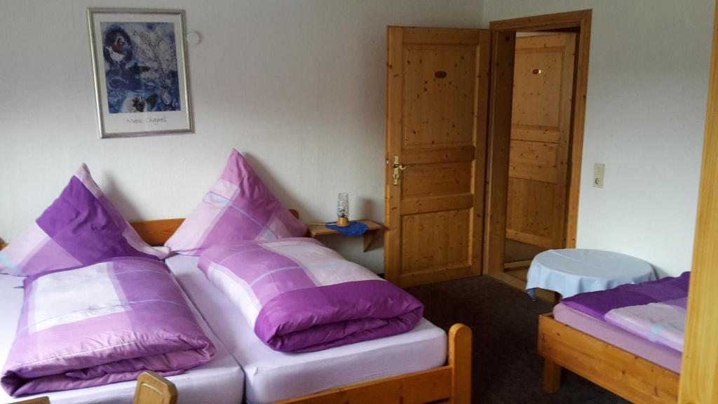 HolzappelにあるBruchhauser Muhleの紫色の枕が備わるベッド2台が備わる客室です。