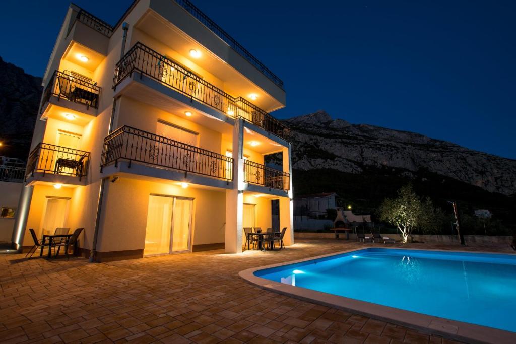 a villa with a swimming pool at night at Apartments Matanovi Dvori in Makarska