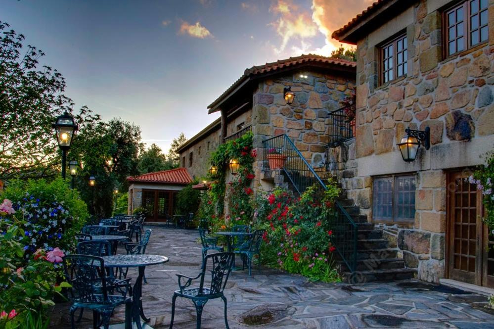 a patio with tables and chairs in front of a building at Quinta Das Escomoeiras in Celorico de Basto