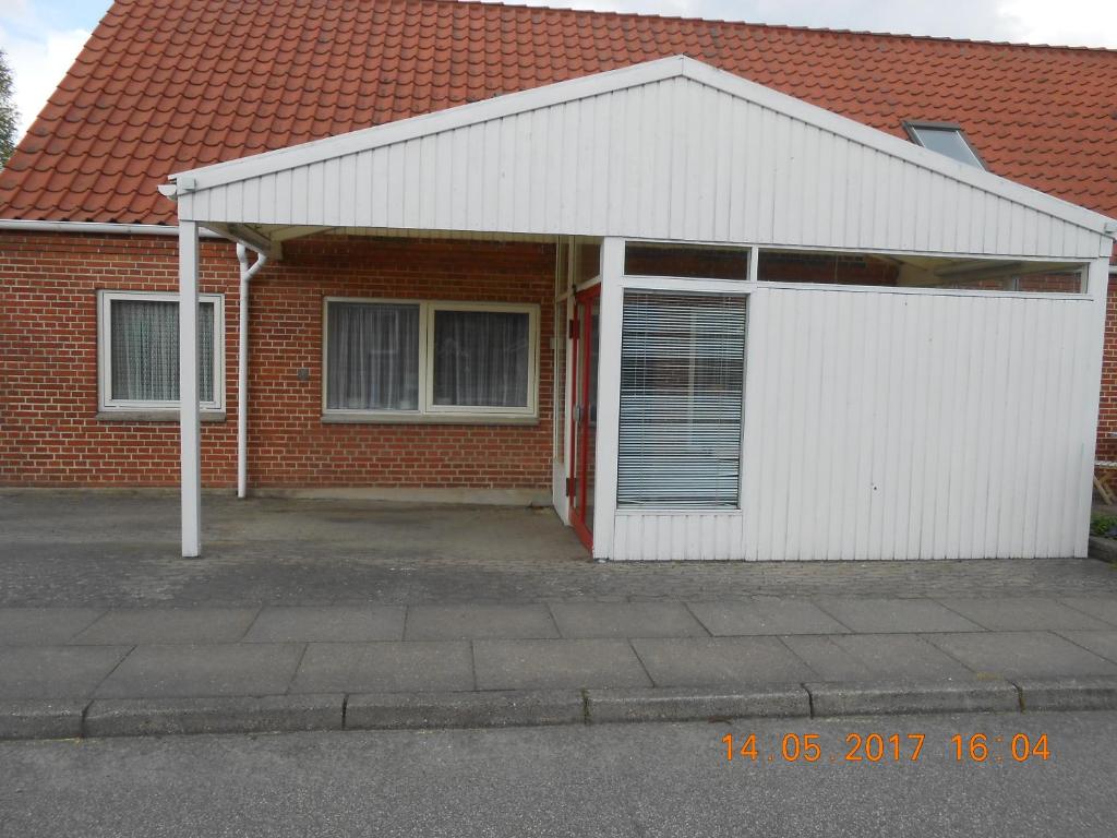 a white garage with a red brick house at Stevnstrup Ferielejlighed in Stevnstrup