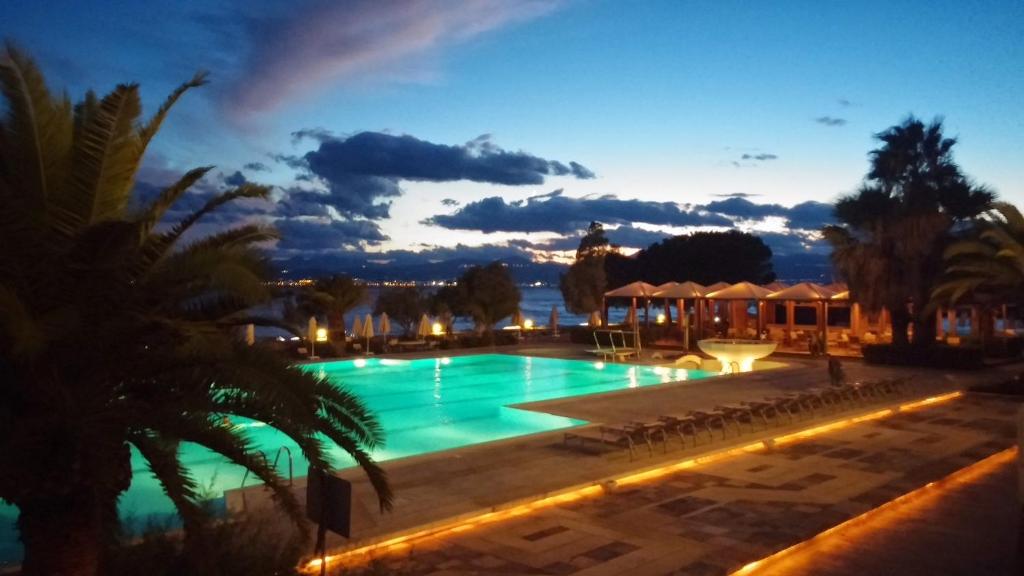 a swimming pool with a resort at night at Ramada Loutraki Poseidon Resort in Loutraki