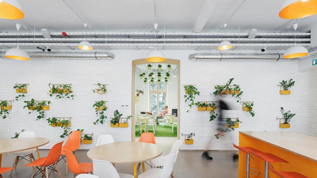 una habitación con mesas, sillas y plantas en la pared en Flow Spaces, en Budapest