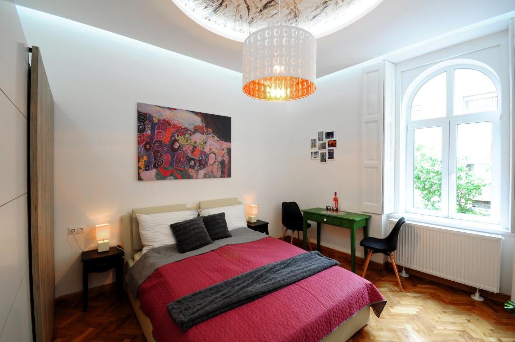 a bedroom with a bed and a table and a chandelier at Stylish Apartman Szeged in Szeged