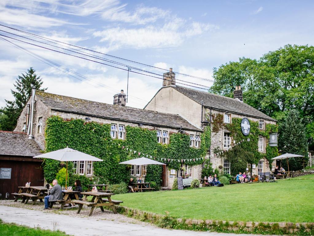 a building with tables and umbrellas in front of it at The Lister Arms in Malham