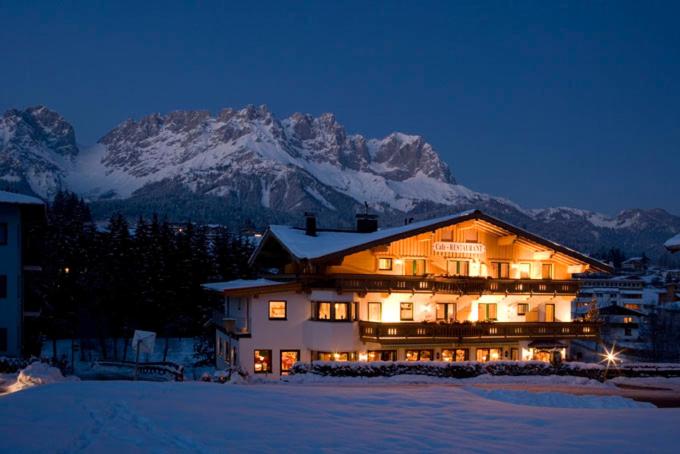 a large building with snow covered mountains in the background at Pension Alexandra in Going am Wilden Kaiser