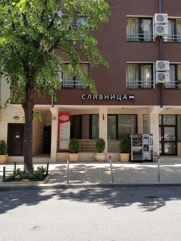 a building with a tree in front of it at Hotel Slivnitsa in Burgas