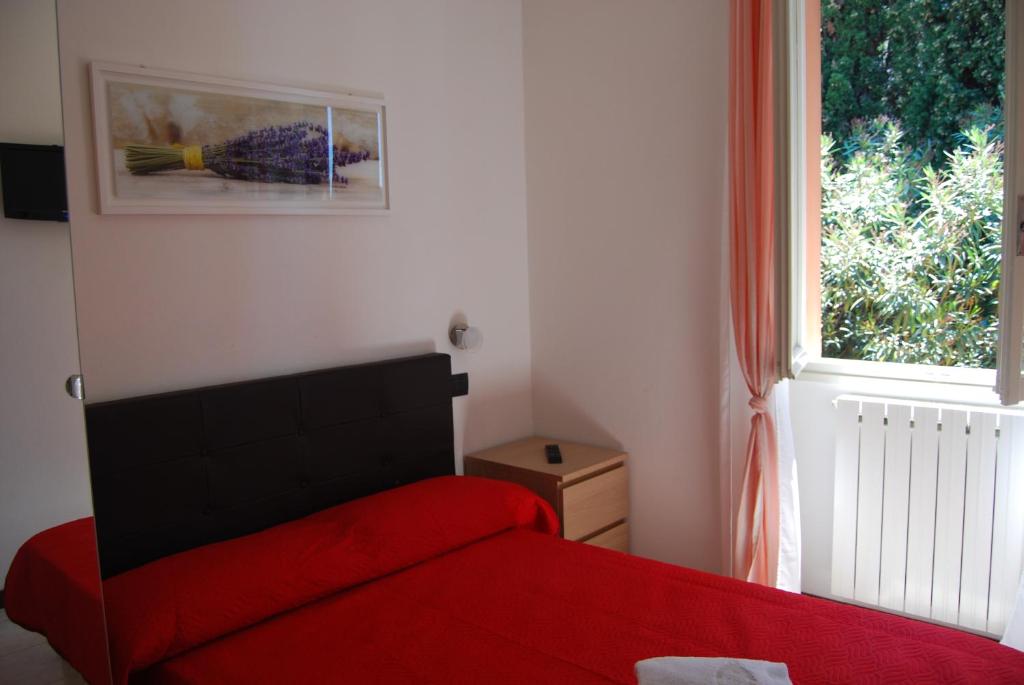a bedroom with a red bed and a window at Appartamenti Corneliani II in Sirmione