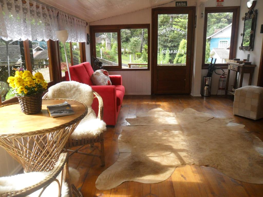 uma sala de estar com um sofá vermelho e uma mesa em Hospedaria Paradouro Caracol em Canela