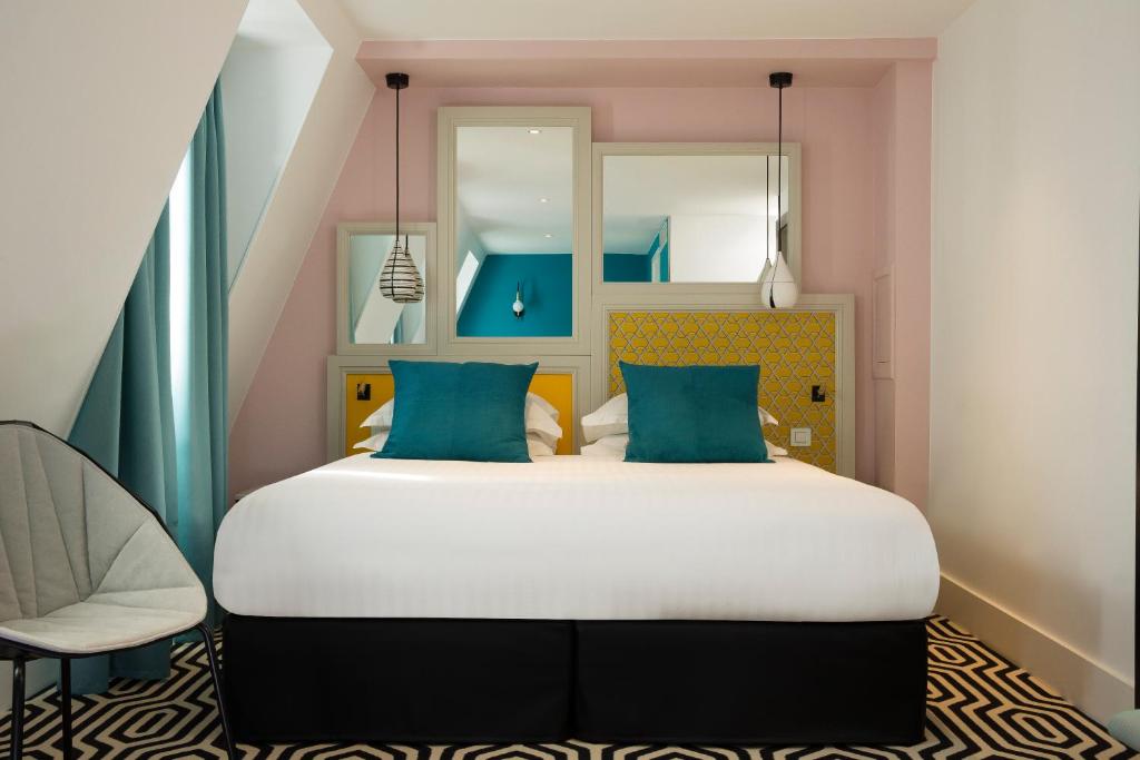 um quarto com uma cama grande e uma cadeira em Hotel Haussmann Saint Augustin em Paris