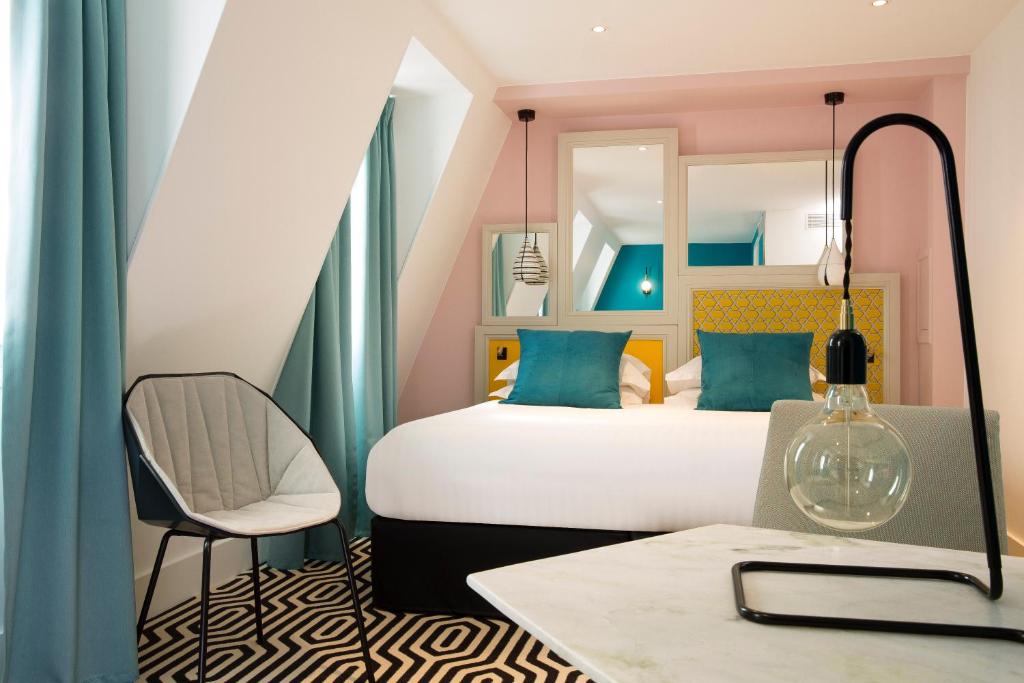 a bedroom with a bed and a chair and a table at Hotel Haussmann Saint Augustin in Paris