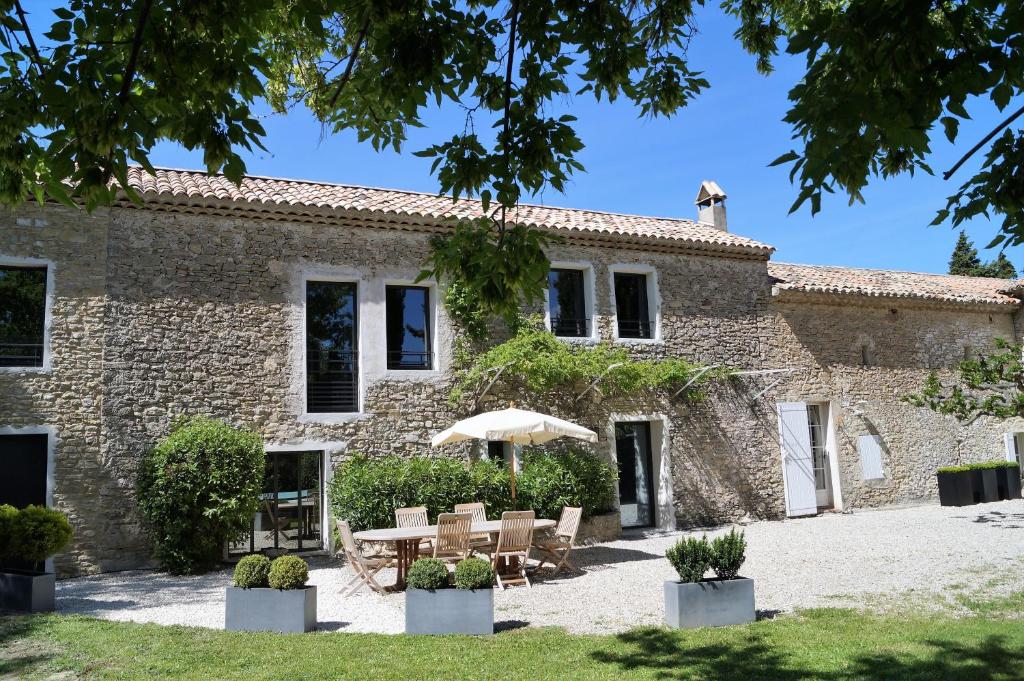 an external view of a building with a table and umbrella at le mas de colongene in Faucon