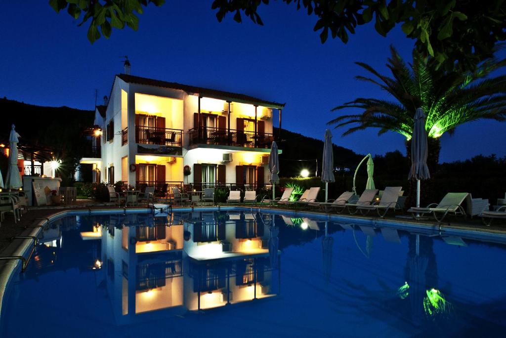 a villa with a swimming pool at night at Pegasus Apartments in Stafylos