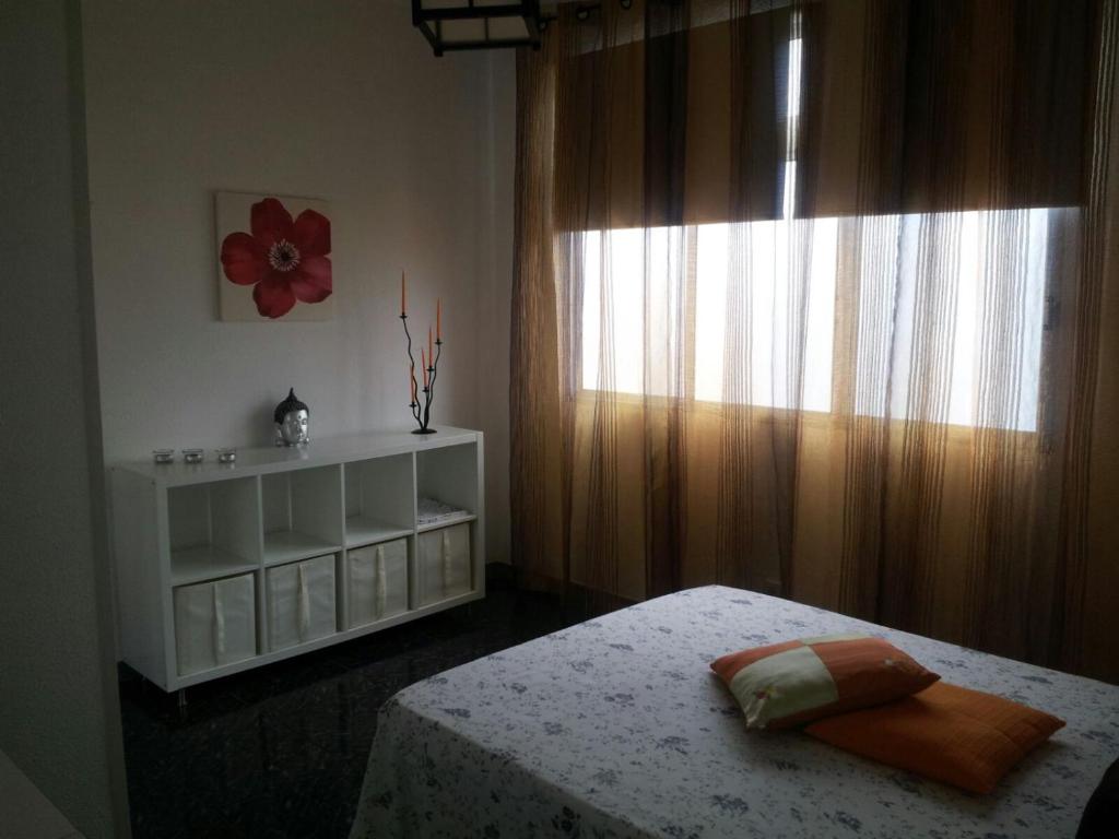 ラスパルマス・デ・グランカナリアにあるAppartamento a La Isletaのベッドルーム1室(ベッド1台付)、花の窓が備わります。