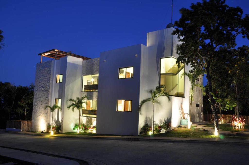 a large white building with palm trees in front of it at Villa Eva Luxury Akumal in Akumal