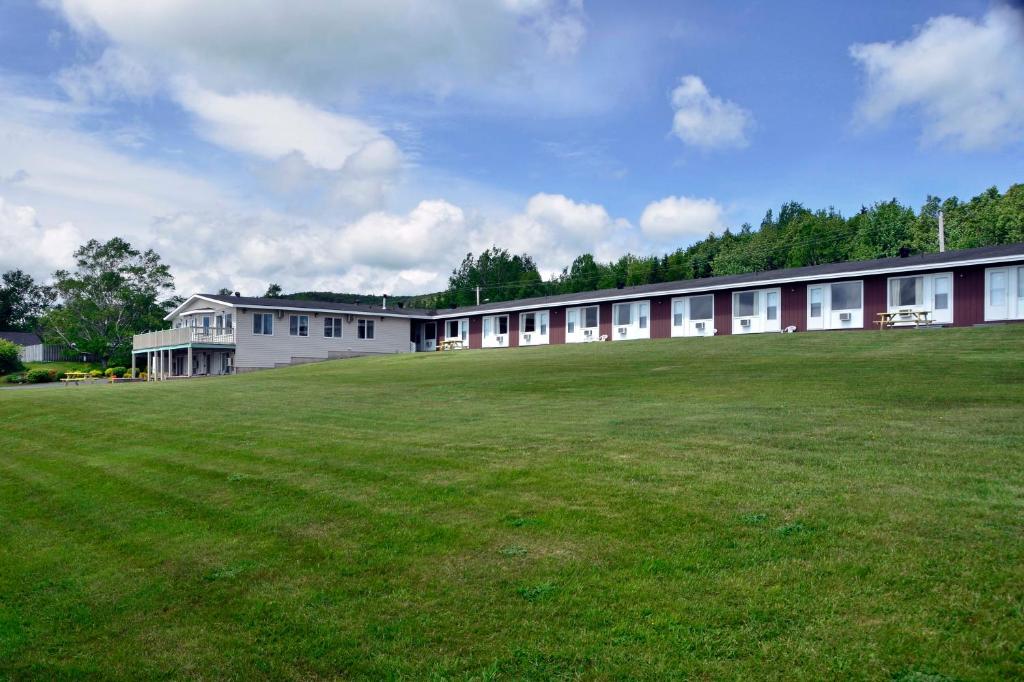 
a large building with a grassy field at Trailsman Lodge & Cape Breton Fried Chicken in Baddeck
