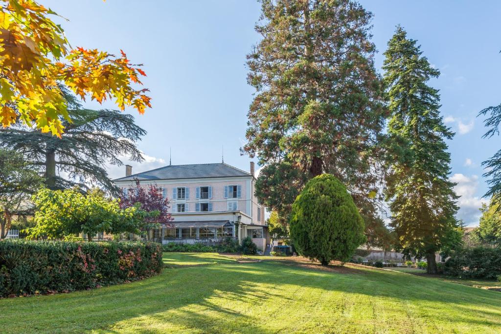 ein großes weißes Haus mit Bäumen und Rasen in der Unterkunft Chateau de Breuil en Beaujolais in Salles-Arbuissonnas