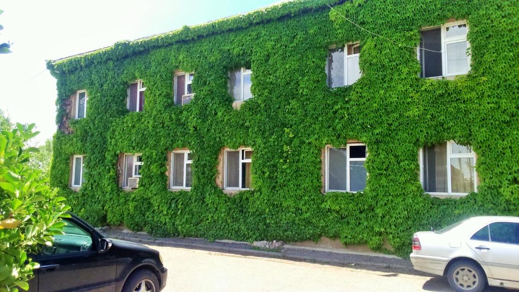 a green building with cars parked in front of it at Hotel Lilo near Airport in Tbilisi City