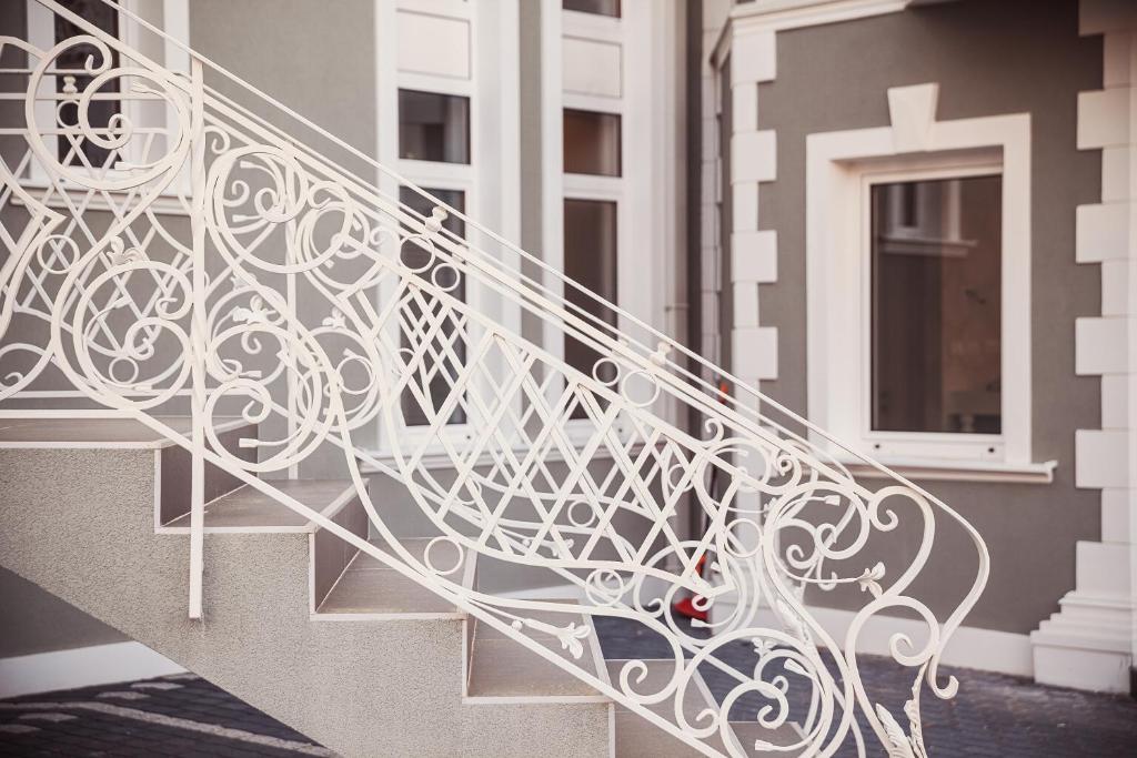 a white metal stair railing in front of a building at Castello Boutique Hotel in Čačak