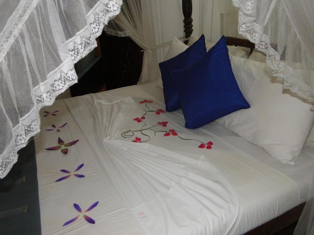 a white bed with flowers on top of it at Thambapanni Retreat in Unawatuna