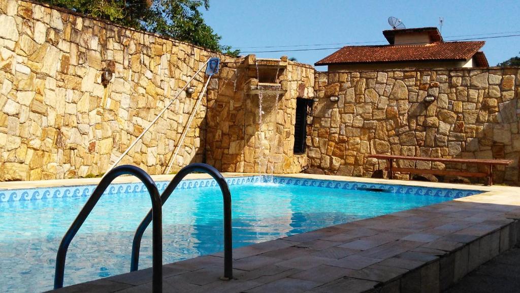 una piscina junto a una pared de piedra en Ipê Suites Juquehy, en Juquei