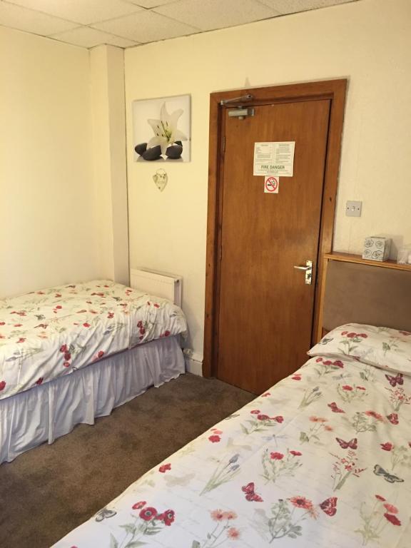 a room with two beds and a wooden door at Camelot House in Blackpool