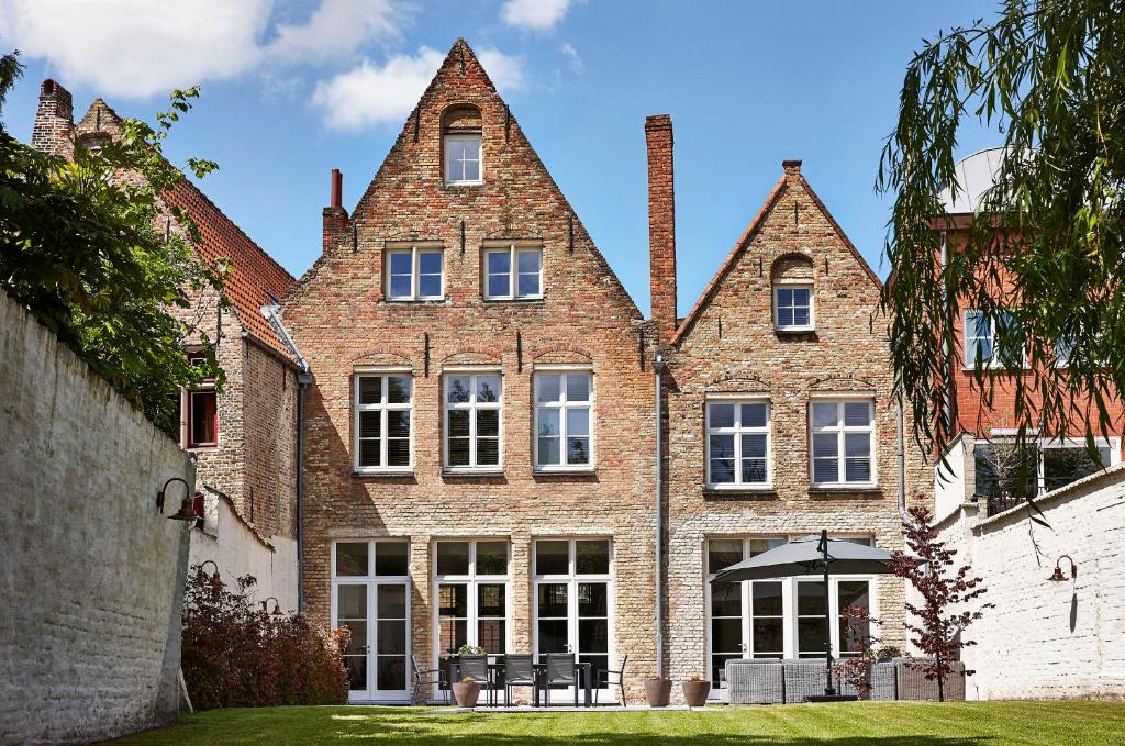 a large brick building with windows on a lawn at La Maison de Nathalie in Bruges