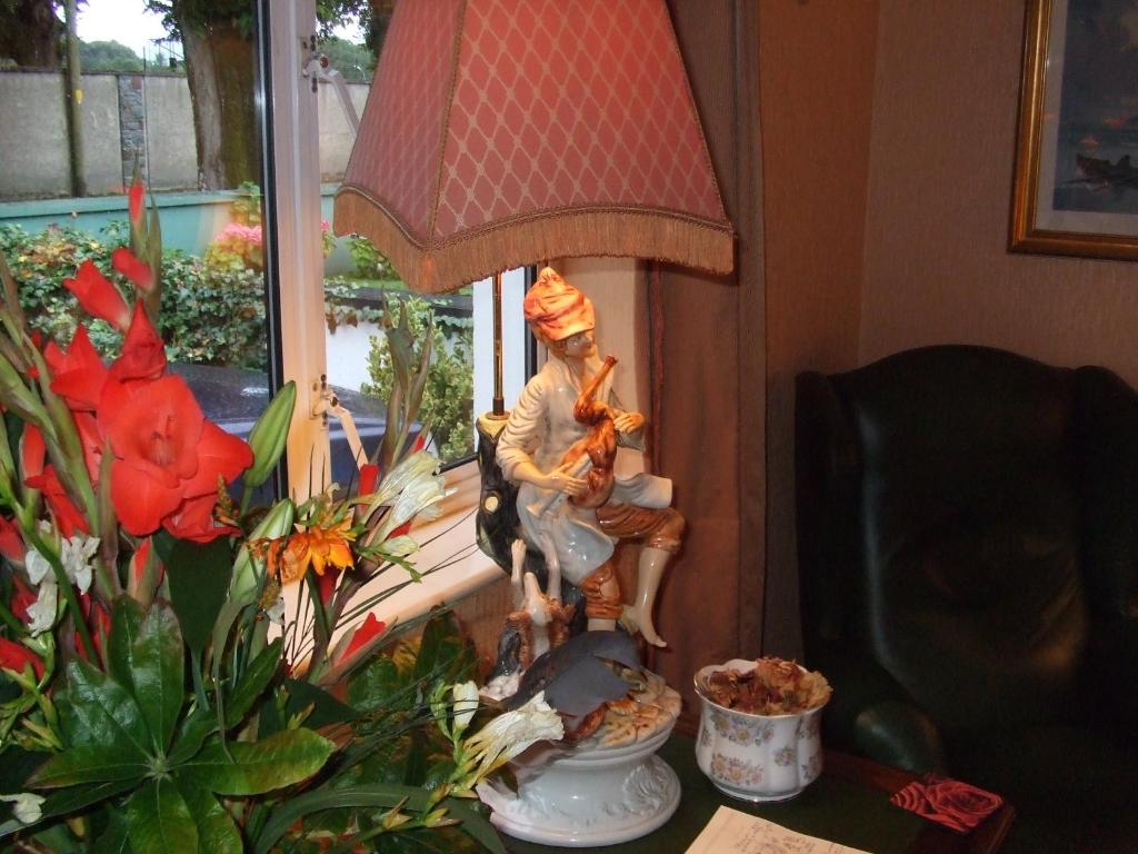 a statue of a woman sitting in a chair next to a window at Windway House in Killarney