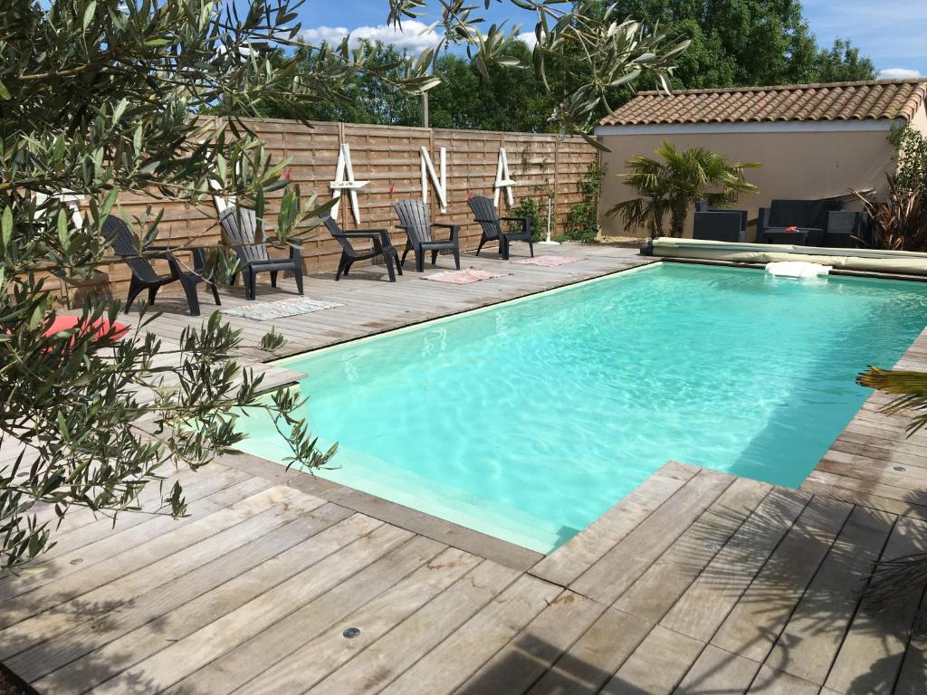 une piscine avec des chaises et une terrasse en bois dans l'établissement CosyStudio Site du Futuroscope, à Chasseneuil-du-Poitou