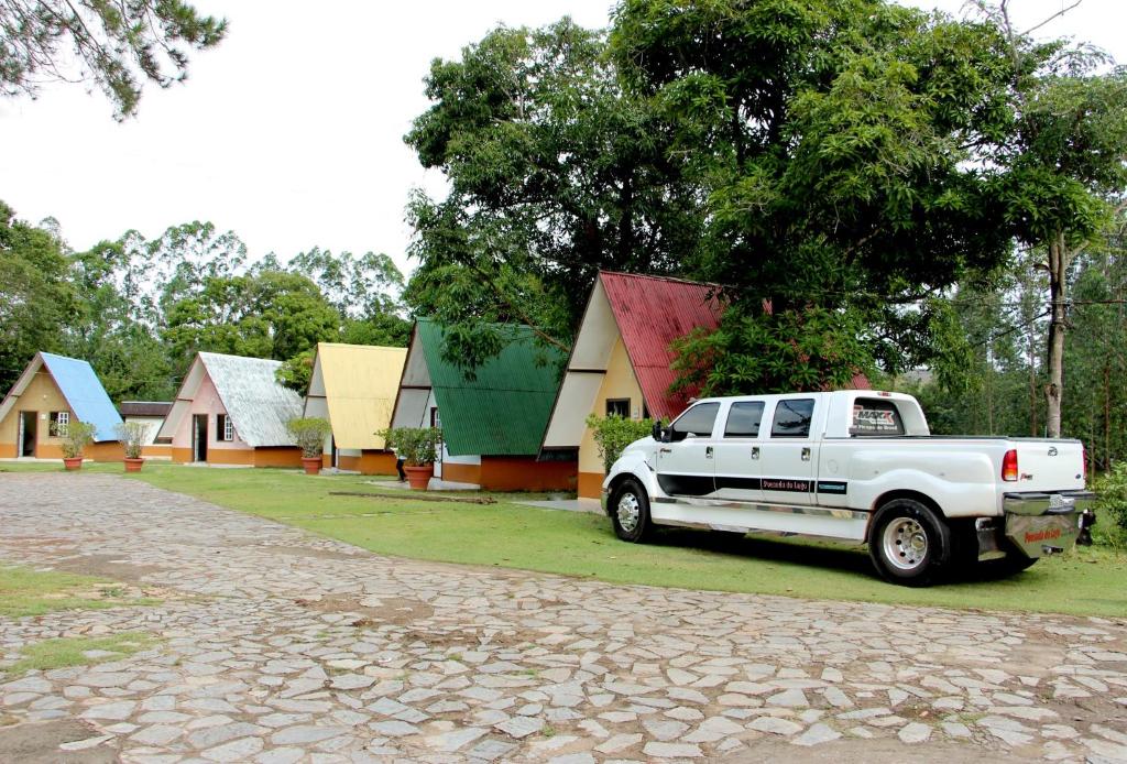 un camion blanc garé devant un groupe de maisons dans l'établissement Pousada do Lago Ltda, à Conceição do Mato Dentro