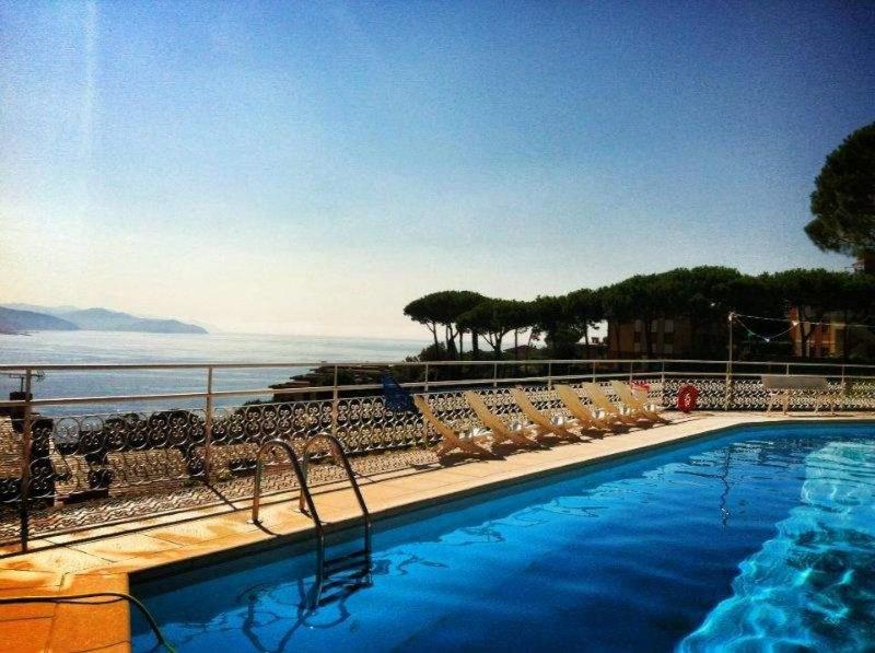 a swimming pool with chairs and a view of the ocean at Residence Portofino Est in Rapallo