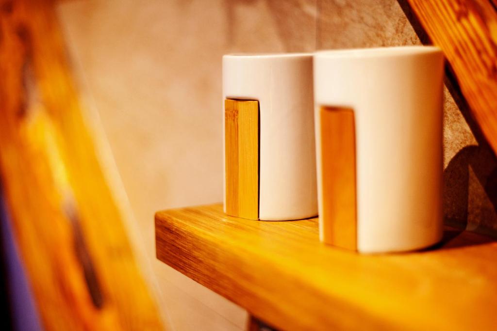 two white cups sitting on a wooden shelf at Hotel Kepplers Ecke in Wingerode