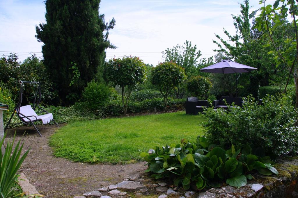 un jardín con sombrilla, sillas y plantas en Tapada Flats, en Viseu