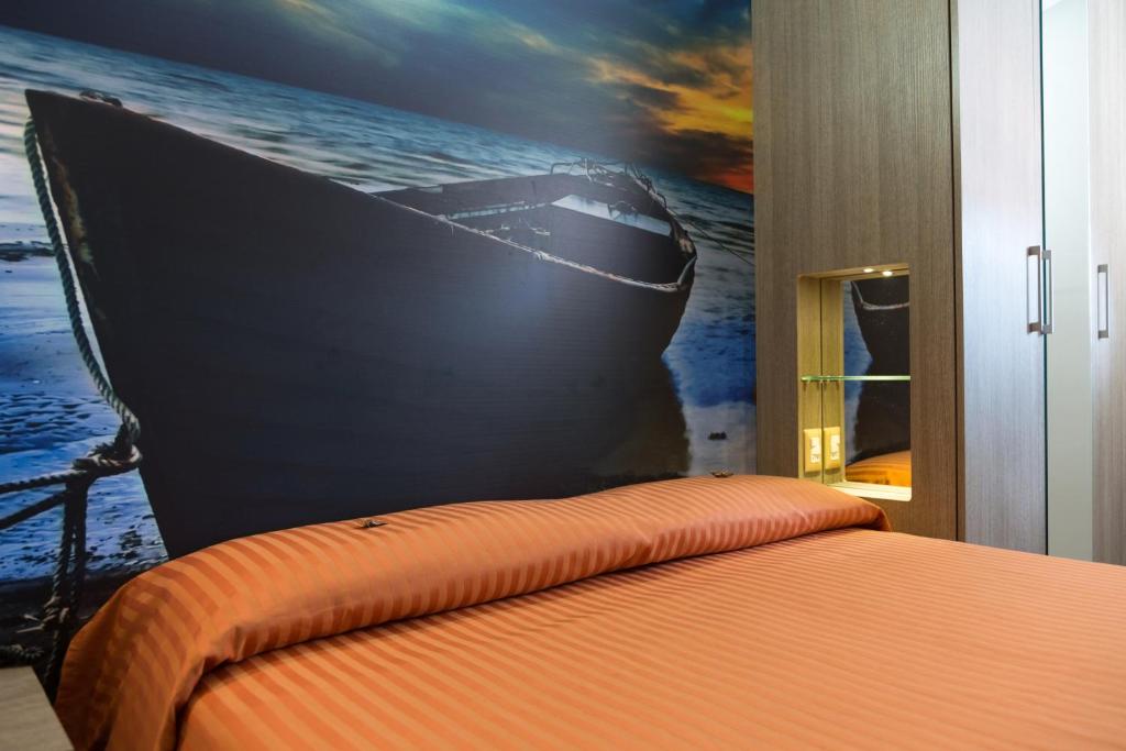 a bedroom with a painting of a boat on the wall at Hotel Miramare in Pineto