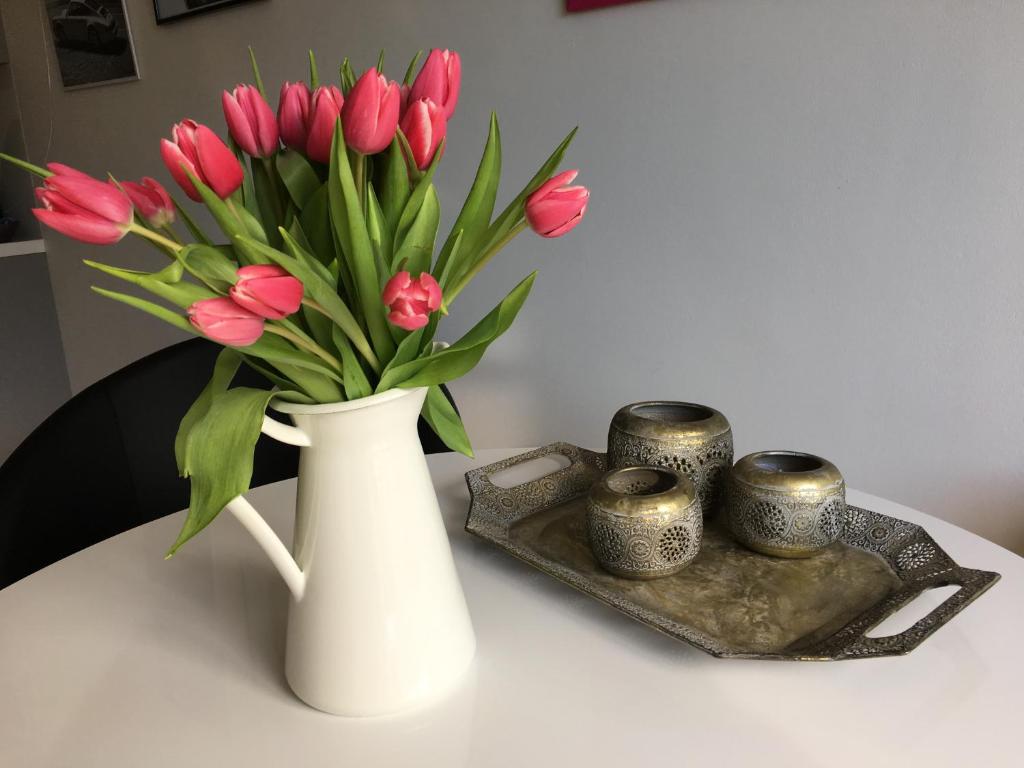 a white vase with pink tulips in it on a table at Erholen Garantiert in Dresden