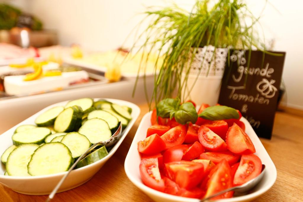 two bowls of tomatoes and cucumbers on a table at Hotel am Peterstor in Regensburg