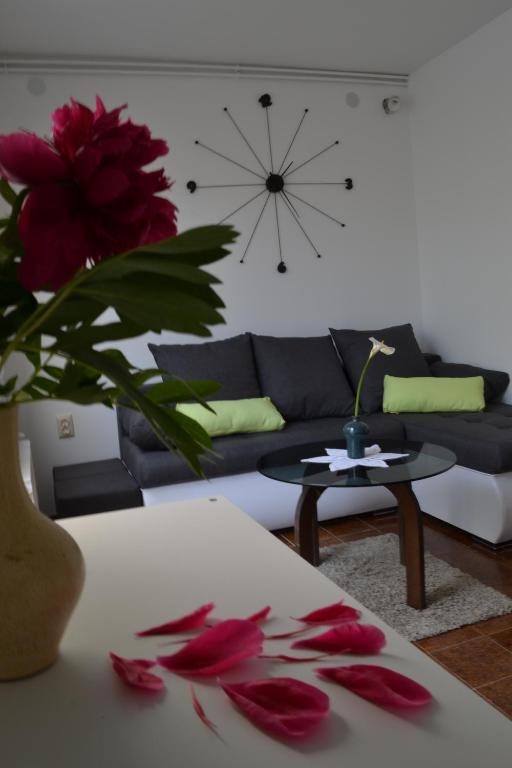ein Wohnzimmer mit einem Sofa und einem Tisch mit roten Blumen in der Unterkunft Apartment Luli in Pula