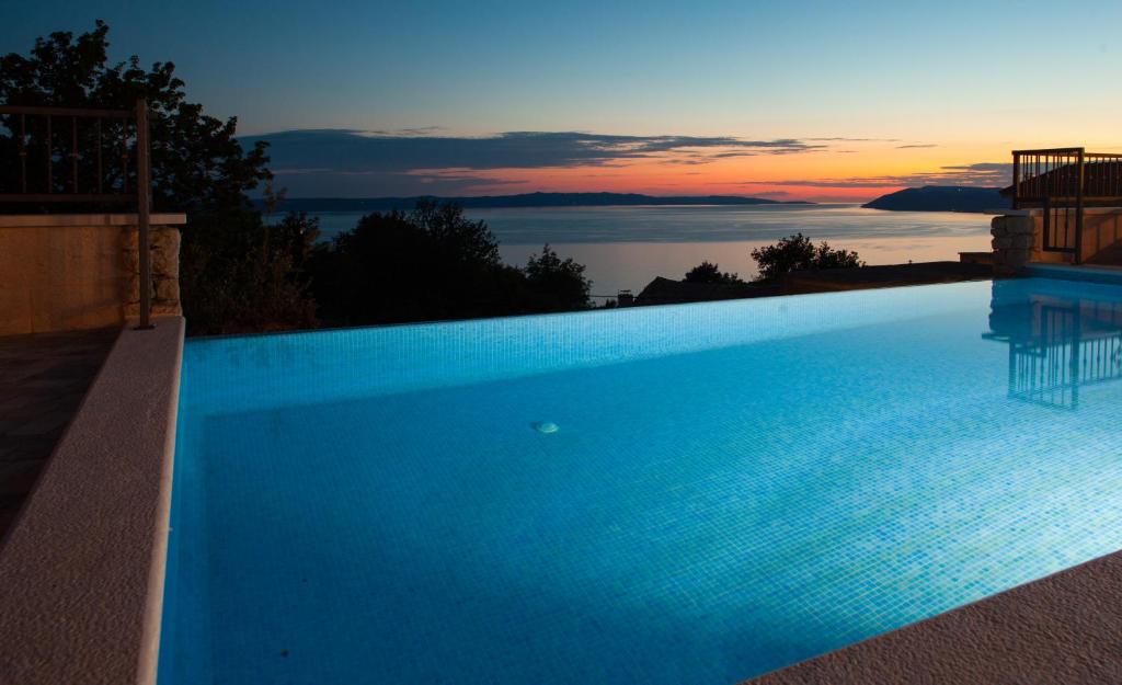 una grande piscina blu con un tramonto sullo sfondo di Villa "Roko" a Tučepi