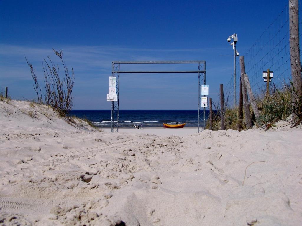 a gate on a beach with the ocean in the background at Apartament Białe Piaski in Dębki