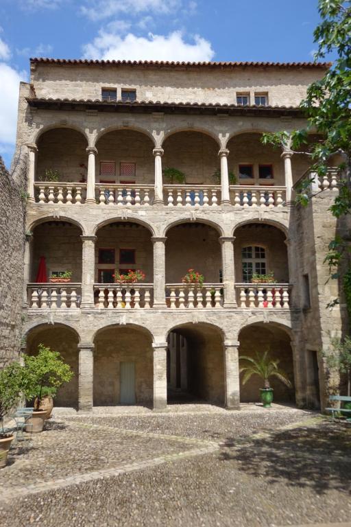 - un grand bâtiment en pierre avec un balcon et des fleurs dans l'établissement Hotel D´ Alfonce, à Pézenas