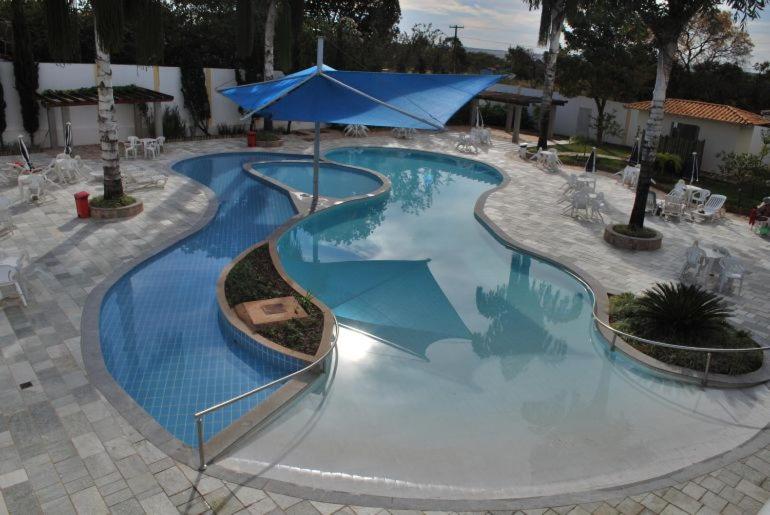 una gran piscina con una gran sombrilla azul en diRoma Resort - Achei Ferias, en Caldas Novas